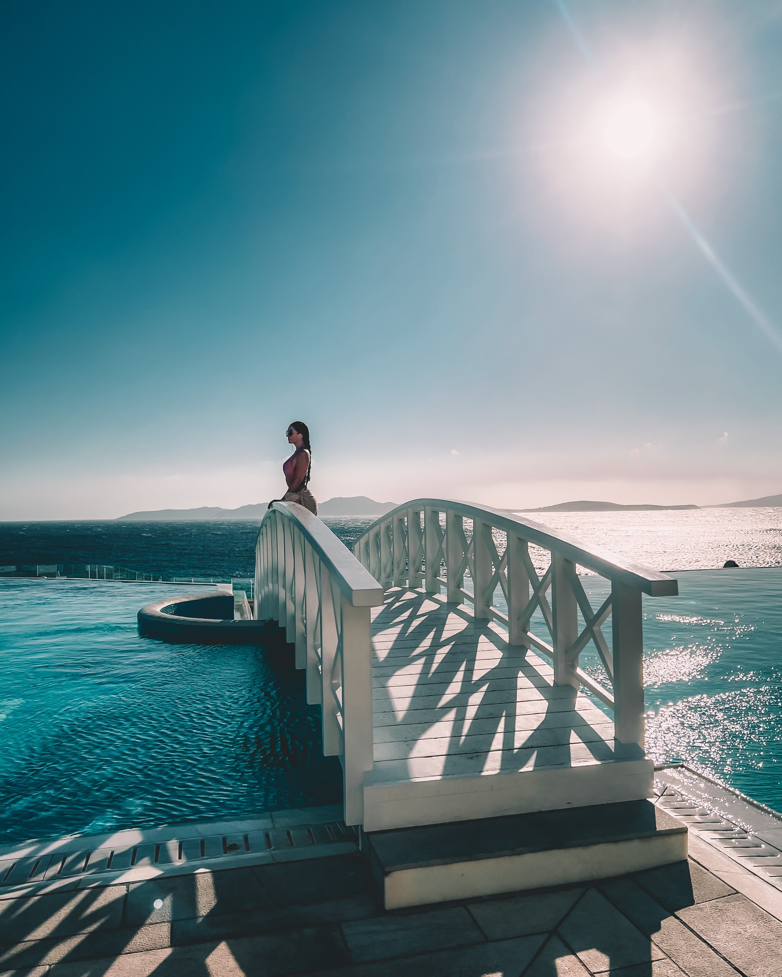 Woman on white bridge over turquoise water
